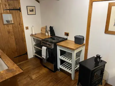 a kitchen with a stove and a wooden table at The carriage in Three Cocks Junction