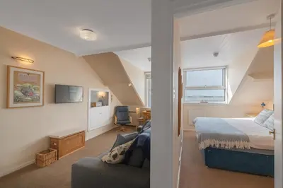 a bedroom with a bed and a chair in a room at Beach Front flat in Aberdovey in Aberdyfi