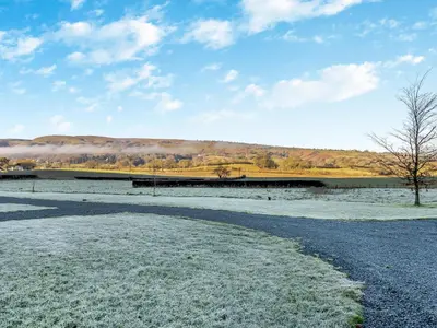 a snow covered field with a bridge in the background at The Farmhouse - Uk48653 in Church Stretton