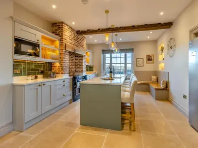 a large kitchen with white cabinets and a large island at The Farmhouse - Uk48653 in Church Stretton