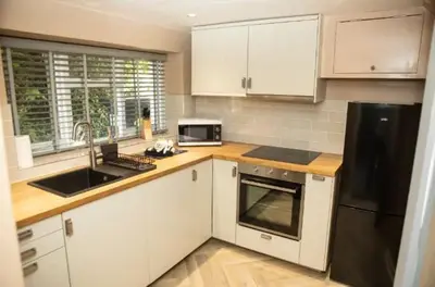 a kitchen with white cabinets and a black refrigerator at The House of Gnarrr in Machynlleth