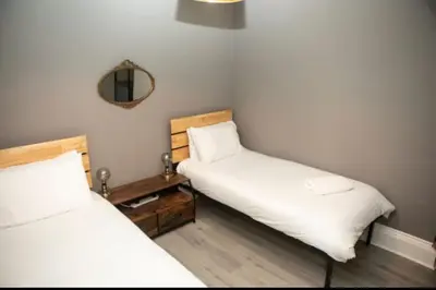 two beds in a small room with a mirror at The House of Gnarrr in Machynlleth