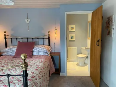 a bedroom with a bed and a bathroom with a toilet at Secluded farmhouse with views in Cwrt-newydd