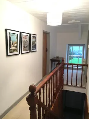 a stairway with three pictures on the wall at Secluded farmhouse with views in Cwrt-newydd