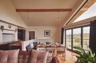 an open living room with a table and chairs at Upper Tumble Cottage in Montgomery
