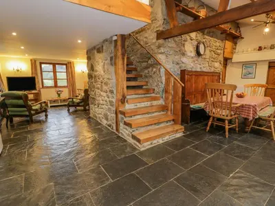 a living room with a stone staircase and a table at Ysgubor in Machynlleth
