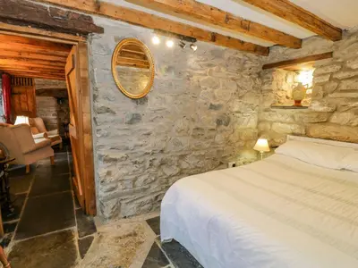 a bedroom with a bed and a stone wall at Ysgubor in Machynlleth