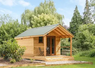 a wooden cabin with a porch in a garden at Acksea Lodges in Oswestry