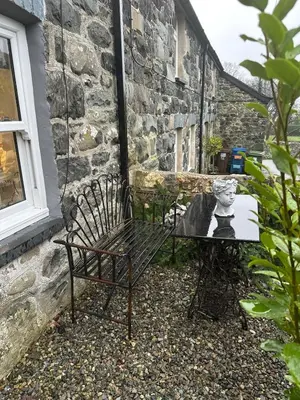 a bench and a table in front of a building at Little Cottage, Llwyngwril in Llwyngwril