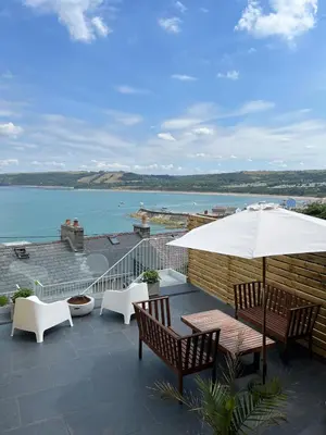 a patio with a table and chairs and an umbrella at Nant Llys - Spectacularly placed with sea views in New Quay