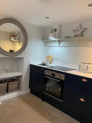 a kitchen with a black oven and a sink at Nant Llys - Spectacularly placed with sea views in New Quay