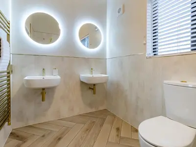 a bathroom with two sinks and a toilet and two mirrors at Root - Uk47733 in Mochdre