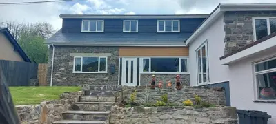 a house with a stone retaining wall in front of it at The Pantry in Erwood