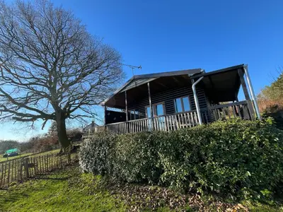 a house on top of a hill with a tree at Red Kite Lodge in Clyro