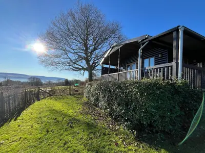 a house with a fence next to a tree at Red Kite Lodge in Clyro