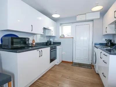 a kitchen with white cabinets and a microwave at Ael Y Don in Harlech