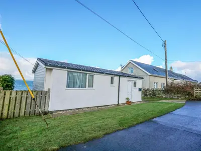 a white house with a fence in a yard at Ael Y Don in Harlech