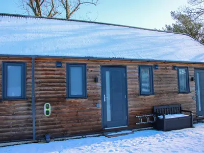 a log cabin with a bench in the snow at Stiper View Barn 1 in Shrewsbury
