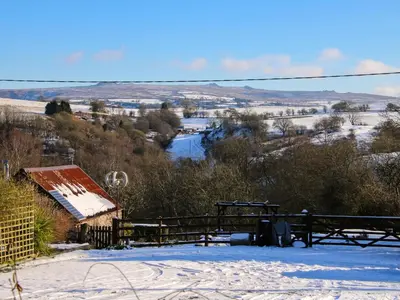 a snow covered hill with a farm and a river at Stiper View Barn 1 in Shrewsbury