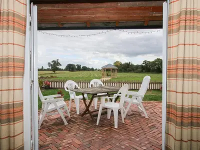 a patio with a table and chairs and a gazebo at Millstone Cottages - Millstone Cottage in Shrewsbury
