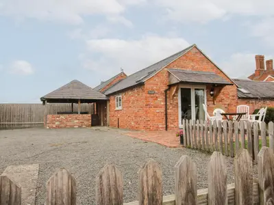 a brick house with a fence in front of it at Millstone Cottages - Millstone Cottage in Shrewsbury
