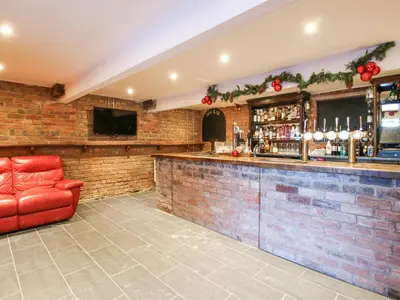 a bar with a red leather chair in a room at Millstone Cottages - Granary Cottage in Shrewsbury