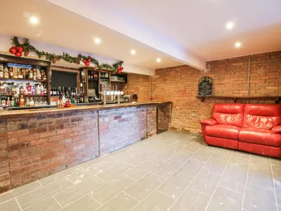 a bar with a red couch in a room at Millstone Cottages - Granary Cottage in Shrewsbury