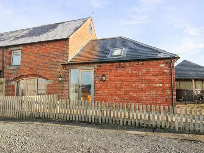 a brick house with a fence in front of it at Millstone Cottages - Granary Cottage in Shrewsbury