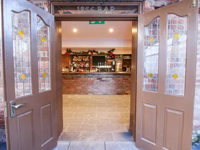 an open door with a bar in the background at Millstone Cottages - Middle Cottage in Shrewsbury