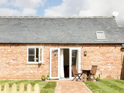 a brick cottage with a picnic table in front of it at Millstone Cottages - Middle Cottage in Shrewsbury