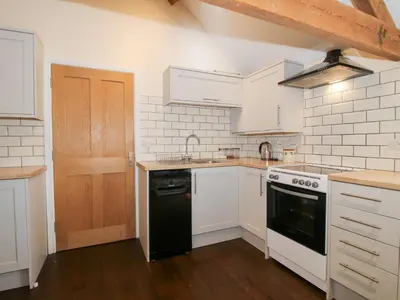 a kitchen with white cabinets and a black dishwasher at Millstone Cottages - Breidden View in Shrewsbury