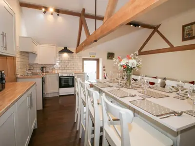 a kitchen with a long table with white chairs at Millstone Cottages - Breidden View in Shrewsbury