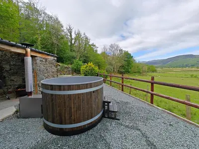 a wooden barrel sitting next to a bench next to a fence at 2 Bed in Penmaenpool oc-m30050 in Arthog