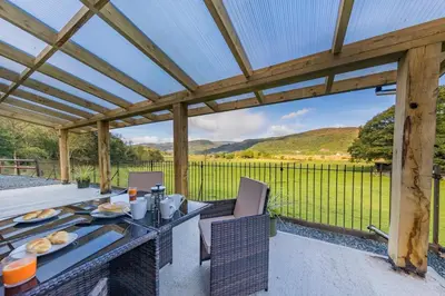 a wooden pergola with a table and chairs on a patio at 2 Bed in Penmaenpool oc-m30050 in Arthog