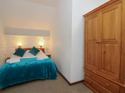 a bedroom with a bed and a wooden cabinet at Y Beudy in Llanybydder