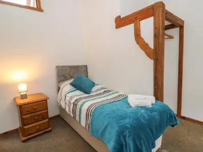 a small bedroom with a bed and a night stand at Y Beudy in Llanybydder
