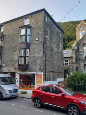 a red car parked in front of a building at Barmouth High Street Family Apartment in Barmouth