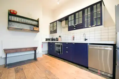 a large kitchen with blue cabinets and a wooden floor at Wilde Lodge by Birch Stays in Bucknell