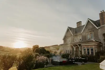 a large house with the sun setting behind it at Wilde Lodge by Birch Stays in Bucknell