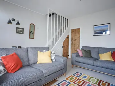 a living room with two couches and a staircase at Gwelfor in Harlech