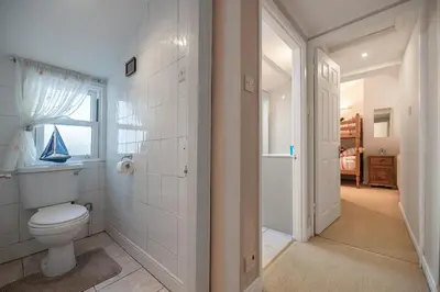 a white bathroom with a toilet and a window at Spacious 3 Bedroom Sea View Flat in Aberdyfi