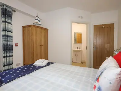a bedroom with a blue bed with a wooden cabinet at Sandcastles in Barmouth