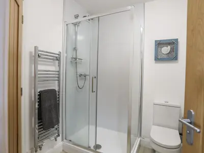 a bathroom with a glass shower with a toilet at Sandcastles in Barmouth