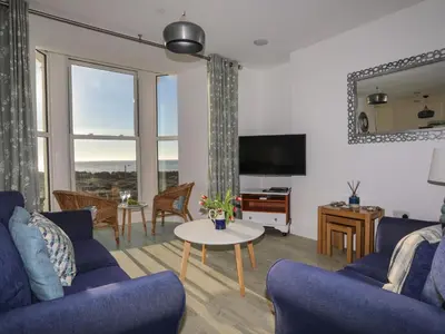 a living room with two blue couches and a table at Sandcastles in Barmouth