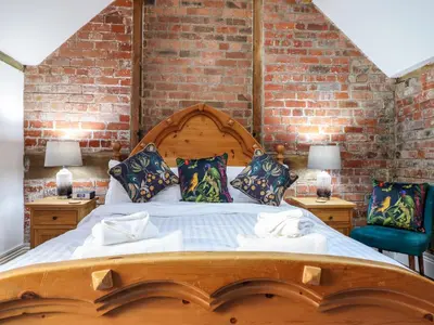 a bedroom with a large wooden bed with two chairs at The Courtyard Cottage in Llangollen
