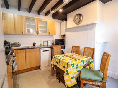 a kitchen with a table and a clock on the wall at The Courtyard Cottage in Llangollen