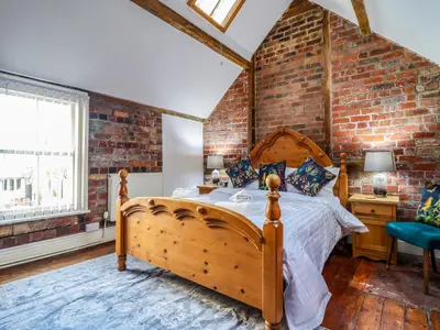 a bed in a room with a brick wall at The Courtyard Cottage in Llangollen