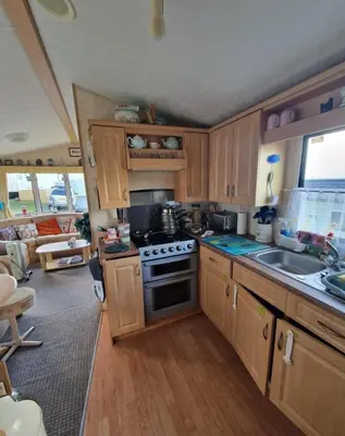 a kitchen with wooden cabinets and a stove top oven at 2 Bed Caravan - Sleeps 4 - Pets - Parking - Wifi in Aberystwyth