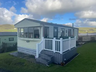 a tiny house with a porch on a lawn at 2 Bed Caravan - Sleeps 4 - Pets - Parking - Wifi in Aberystwyth