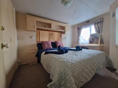 a bedroom with a large bed with blue towels on it at 2 Bed Caravan - Sleeps 6 - Pets - Pool - Parking in Aberystwyth